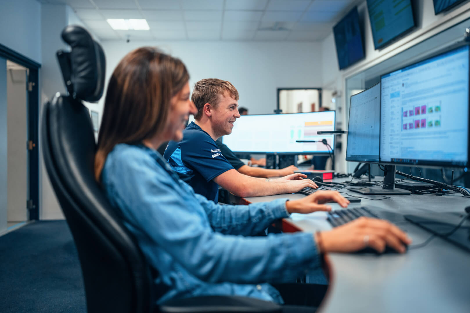 Aerodynamicists at Williams Racing working and looking at their computers while smiling